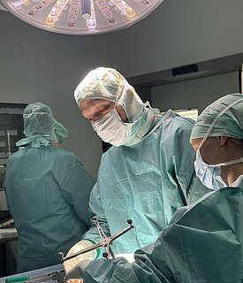 Ein Operateur und zwei Assistent beim operativen Eingriff am Schädel