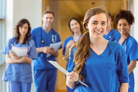 5 Pflegekräfte in blauer Dienstkleidung