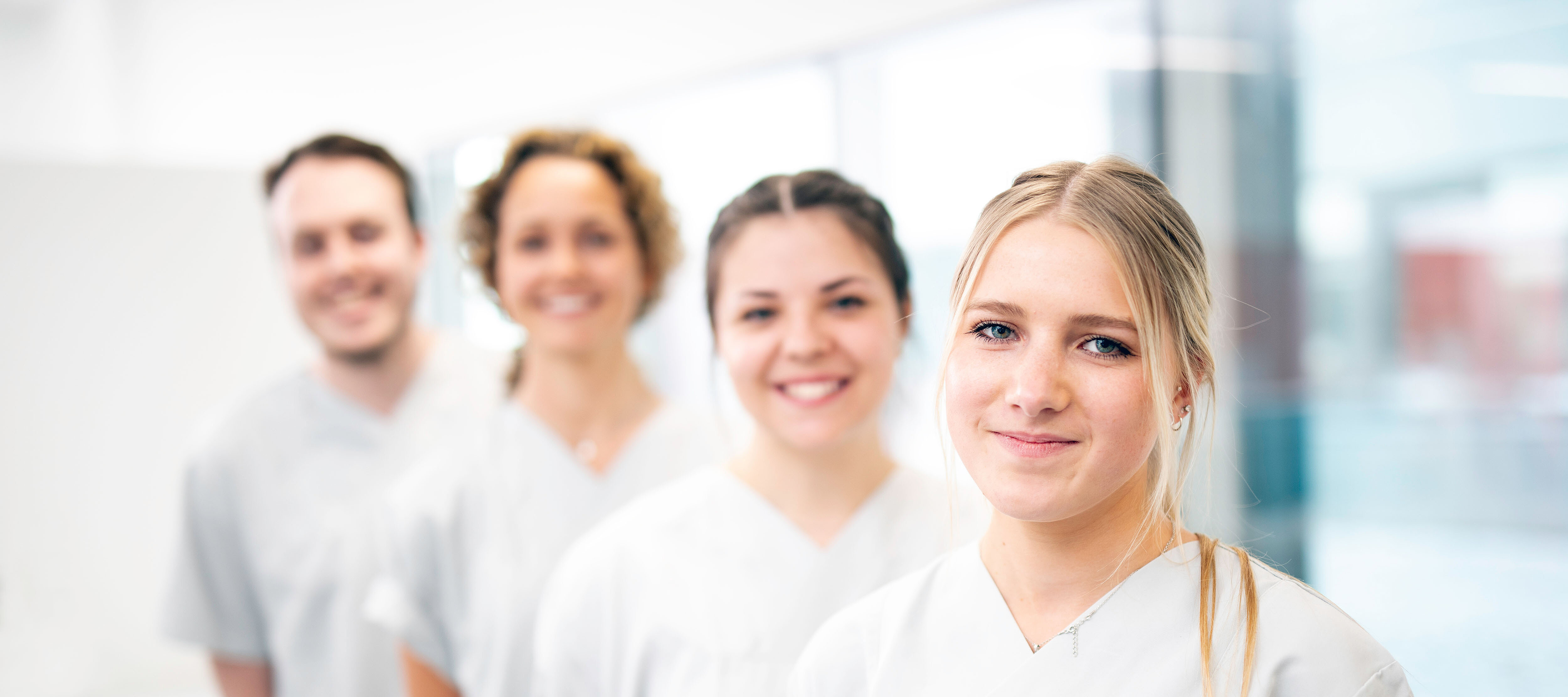 vier Pfelgekräfte in weißen Kasak stehen leicht versetzt hintereinander