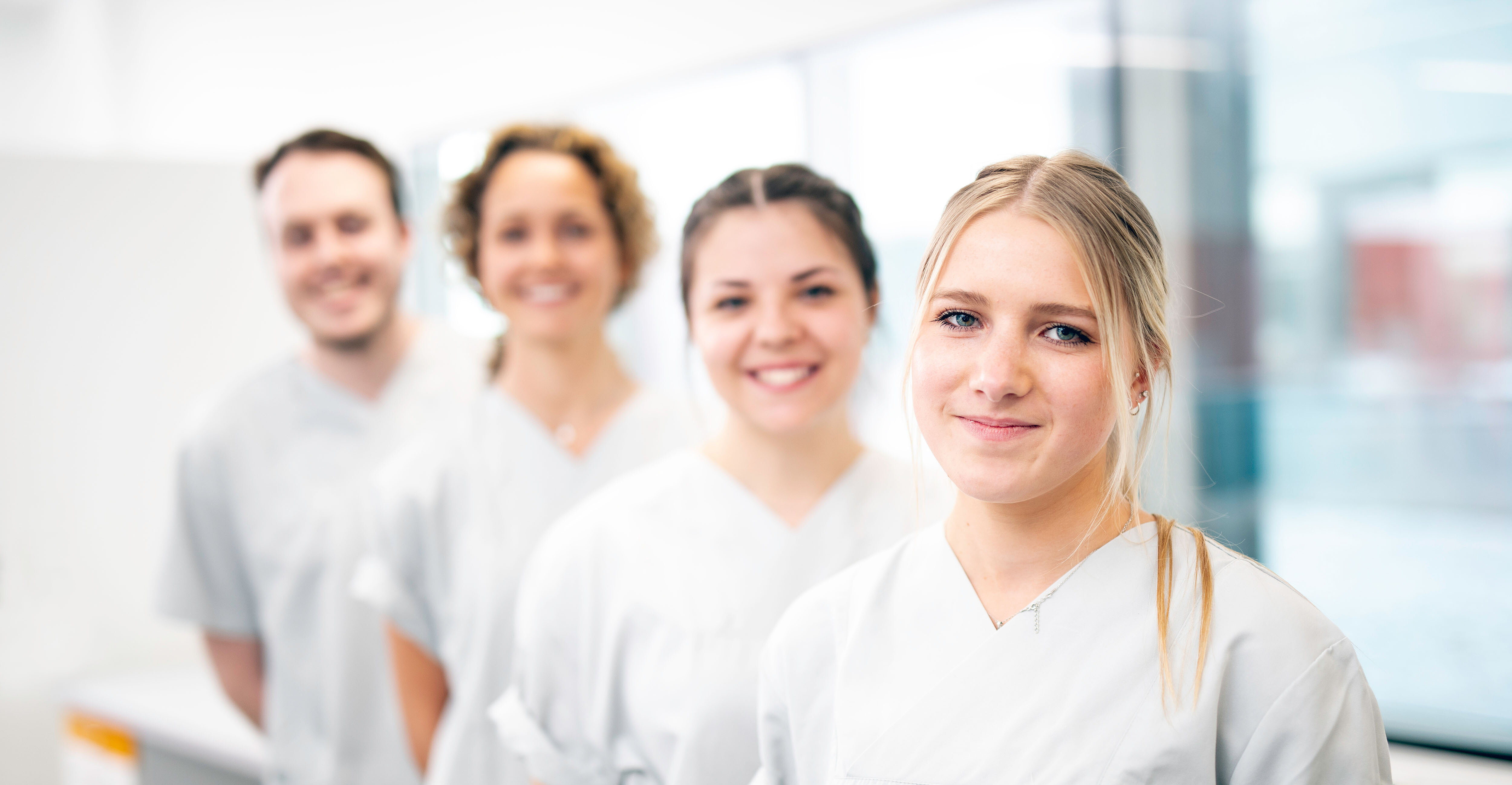 drei Krankenschwestern und ein Krankenpfleger stehen leicht versetzt hintereinander