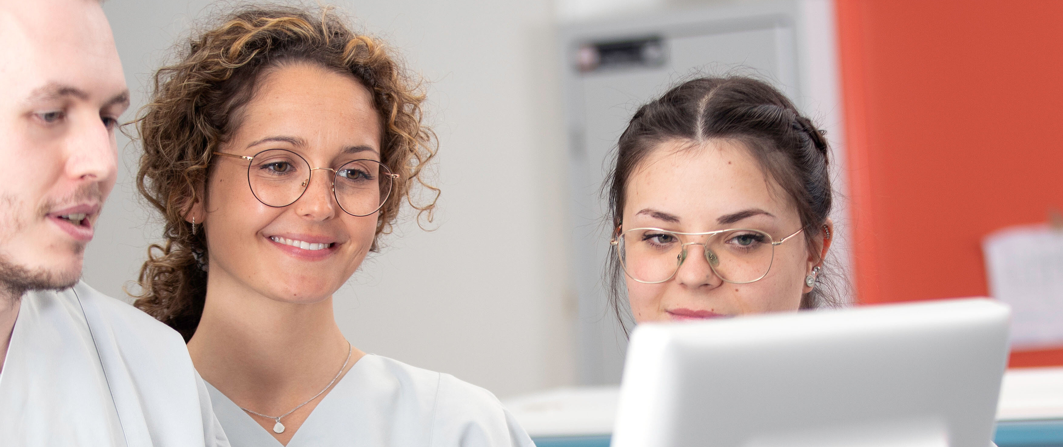 drei Personen blicken in einen Monitor