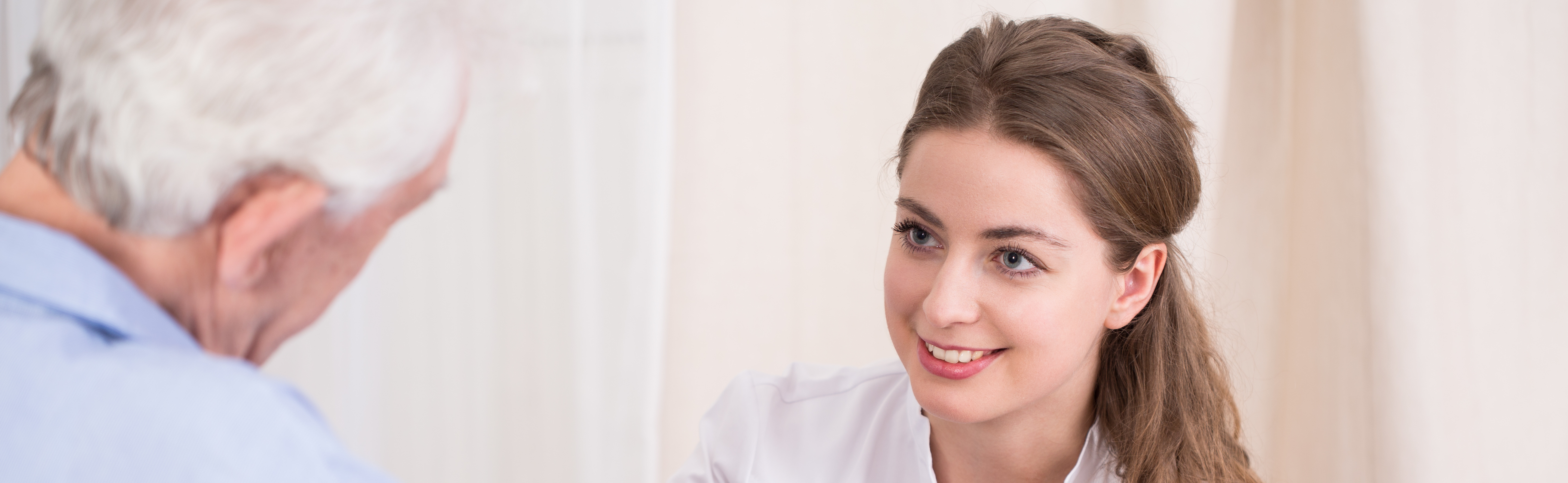 Szenenbild: lächelnde Sozialarbeiterin spricht mit männlichen Patienten